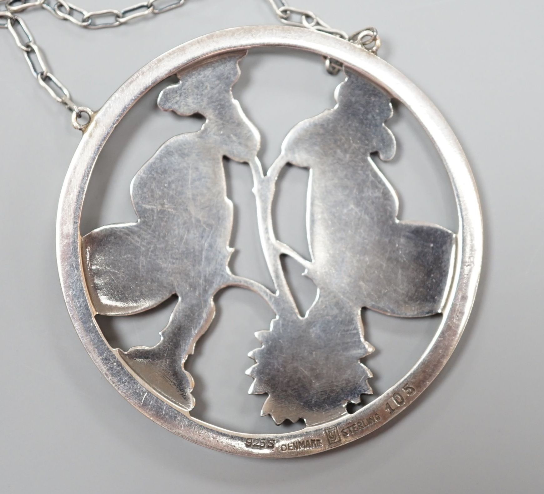 A George Jensen (designed by Arno Malinowski) sterling 'twin moth amid foliage' circular pendant necklace, no. 105, pendant diameter 51mm, chain 54cm.